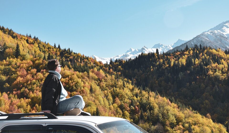 young woman, car, roof, sitting, mountains, sky, car wallpapers, nature, forest, spruce, pine, journey